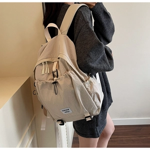 Detail view of cream casual backpack with adjustable straps and side pockets on a model