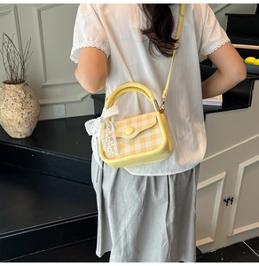 Detailed side view of yellow plaid handbag featuring a white lace bow and round handle