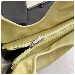 Détail macro de la texture crocodile et fermeture éclair argentée sur le sac