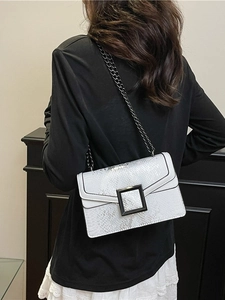 Sac à bandoulière blanc à motif serpent avec boucle en métal noir porté par un modèle