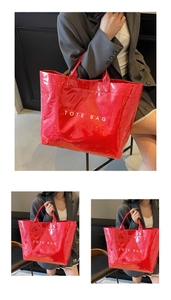 Detail view of large red glossy PVC tote bag with white TOTE BAG text print on surface