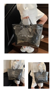 Detail of black glossy tote bag with crinkled texture and white TOTE BAG lettering