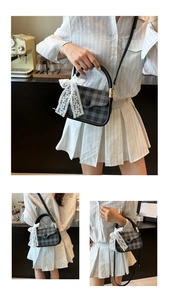 Detail of plaid handbag with black buckle and white lace bow in a cafe setting