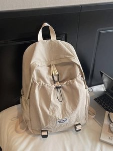 Minimalist cream nylon backpack with drawstring front pocket for students and daily commute