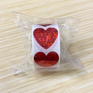 Dettaglio di rotolo di adesivi a cuore rosso glitterati per decorazioni regalo