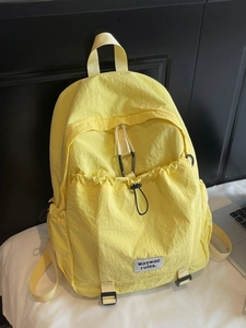 Minimalist yellow nylon backpack with drawstring front pocket and adjustable straps