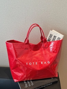 Glossy red large capacity PVC tote bag with white text on fashion magazine background