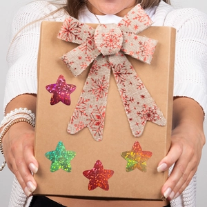 Roll of holographic laser star stickers for decoration on a gift box held by a person