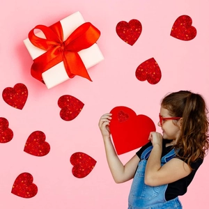 Ragazza tiene adesivi a cuore rosso lucido per decorazioni regalo festive