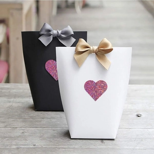 Dettaglio di sacchetti regalo di lusso con fiocchi di seta e adesivi olografici a cuore