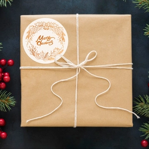 Golden Merry Christmas stickers with wreaths on brown gift boxes with pine needles