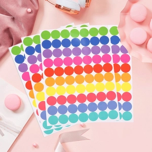 Colorful round dot stickers for DIY labeling arranged in a fan shape on a pink background