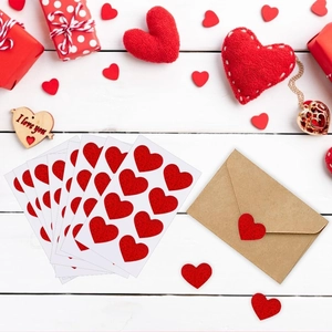 Red glitter heart stickers for Valentine gift wrapping and envelope seals on white wood