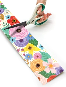 Close-up of cutting colorful floral border stickers with scissors for DIY crafts