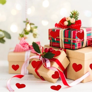 Close-up of glittery red heart stickers on kraft gift boxes with warm festive bokeh lights