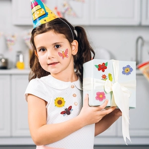 Fille tenant une boîte cadeau décorée d'autocollants colorés papillons et fleurs pour la fête