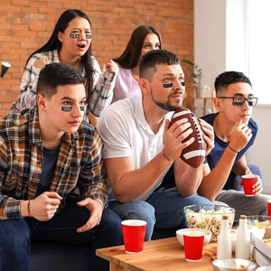 Close-up of sports fans wearing black eye stickers and USA face decals at a watch party