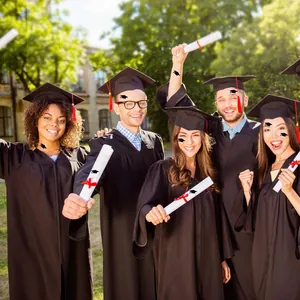 Close-up of black graduation gowns with caps and red tassels in an outdoor campus setting