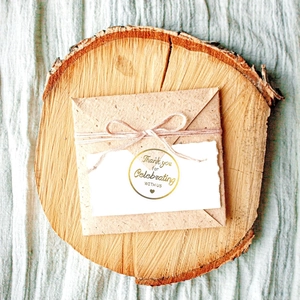 Close-up of gold foil thank you sticker on kraft envelope with rustic twine and card
