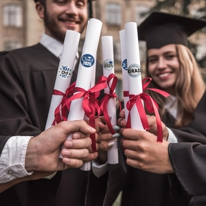 Detail of graduation stickers on scrolls held by graduates for Class of 2025 celebration
