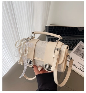 Gros plan du sac crème avec accents de perles, détails en dentelle et fermoir rotatif