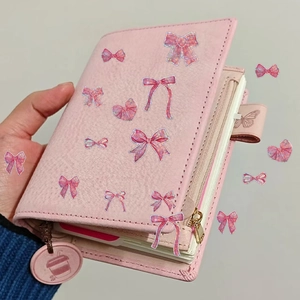 Vue détaillée d'un agenda en cuir rose avec fermeture à nœud et pendentif décoratif rond