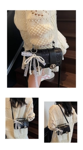 Détail du sac à bandoulière noir avec nœud en dentelle perlée et boucle en métal vintage