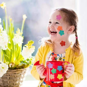 Girl with colorful glitter flower stickers on face and watering can, vibrant playful scene