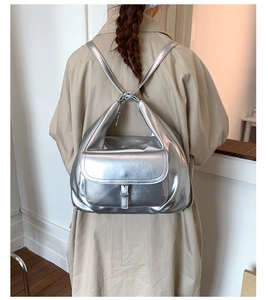 Silver metallic backpack with buckle closure and integrated straps on casual trench coat