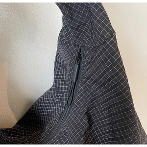 Détail macro du tissu matelassé noir avec surpiqûres quadrillées et fermeture éclair premium