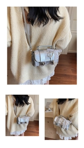 Détail d'un sac cylindrique argenté avec nœud en dentelle et pendentifs en perles