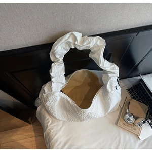 Détail du sac blanc en tissu texturé avec bandoulière plissée pour un look décontracté