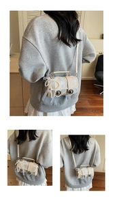 Détail du sac cylindre crème avec nœud en dentelle, chaîne de perles et clous de protection