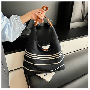 Detail of waterproof nylon bag with white stripes and contrast brown leather handles