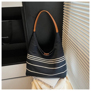 Macro detail of large black nylon tote with white stripes and brown leather handle