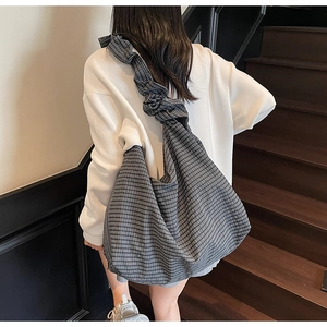 Detailed view of grey checkered tote bag with ruffled shoulder strap worn by a model