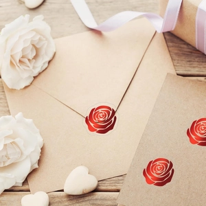 Dettaglio di adesivi a rosa laser usati come sigillo decorativo su busta in carta kraft