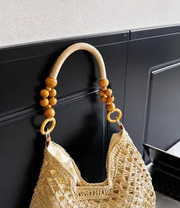 Détail du sac cabas en paille tissée avec poignées en perles de bois et doublure