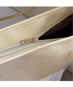 Détail de la fermeture dorée et du motif crocodile sur le sac cabas crème avec doublure