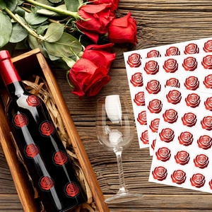 Dettaglio di adesivi a forma di rosa rossa applicati su una bottiglia di vino