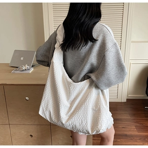 Détail de la texture gaufrée blanche d'un grand sac hobo au design minimaliste et épuré