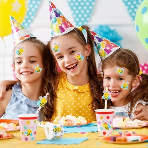 Girls applying cartoon bee stickers on faces and party cups at a birthday celebration