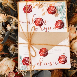 Dettaglio di inviti di nozze con rose rosse e spago rustico in stile elegante