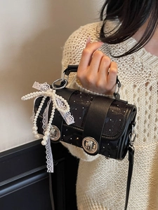 Sac cylindrique noir élégant avec nœud en perles et dentelle tenu par un mannequin