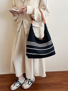 Striped hobo shoulder bag with leather straps on a model in a minimalist setting