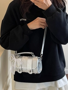 Sac cylindrique argenté métallisé avec nœud en dentelle et perle porté par un mannequin
