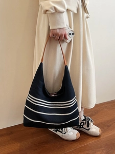 Retro black striped nylon tote bag with leather handles shown on a model in a minimal room