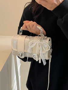 Sac à bandoulière beige avec nœud perlé et rubans en dentelle porté à la main