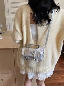 Sac cylindrique argenté brillant avec nœud en dentelle et chaîne de perles porté