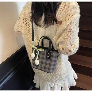 Detail of checkered bucket bag featuring tulip charm and ribbon on model back